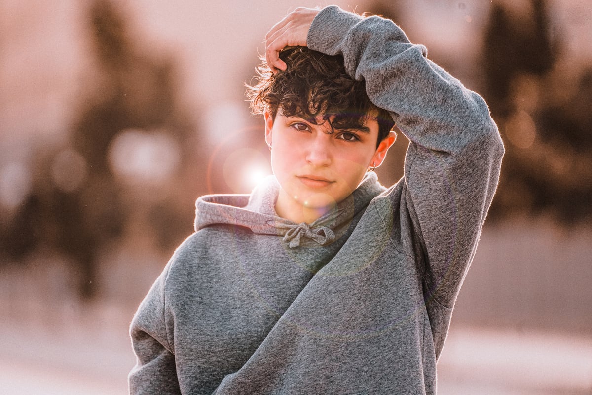 Stylish adolescent touching hair on street in town